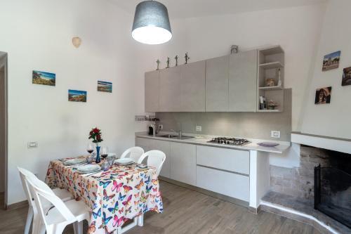una cucina con tavolo e sedie e una cucina con armadietti bianchi di CASA ZEN A GEREMEAS a Cagliari