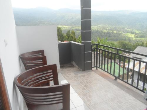 a balcony with two chairs and a view of the mountains at One Homestay and Warung in Munduk