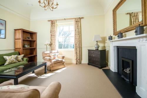 a living room with a fireplace and a green couch at The Bath Priory - A Relais & Chateaux Hotel in Bath