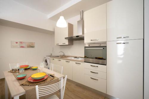 モノーポリにあるWePuglia - Casa Dolcissimaの白いキャビネット、テーブルと椅子付きのキッチンが備わります。