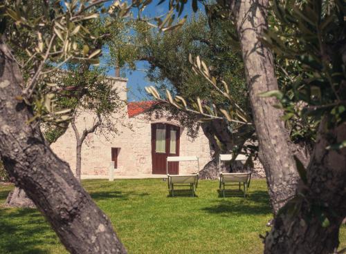 a building with two chairs in a yard with trees at Rifugio di Puglia - Trulli & Dimore in Alberobello
