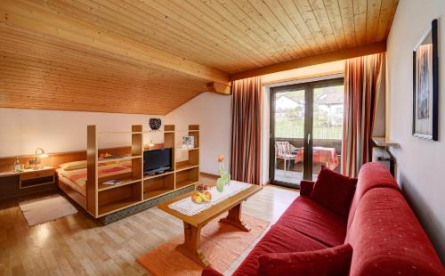 a living room with a red couch and a bed at Apparthotel Taufenbrunn in Parcines