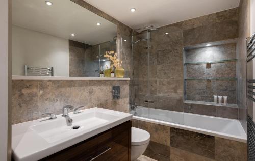 a bathroom with a sink and a tub and a toilet at The Heart of Shepherds Bush - Modern 2BDR Apartment with Garden in London