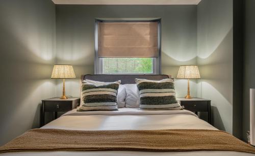 1 dormitorio con 1 cama con 2 lámparas y una ventana en The Heart of Shepherds Bush - Modern 2BDR Apartment with Garden en Londres