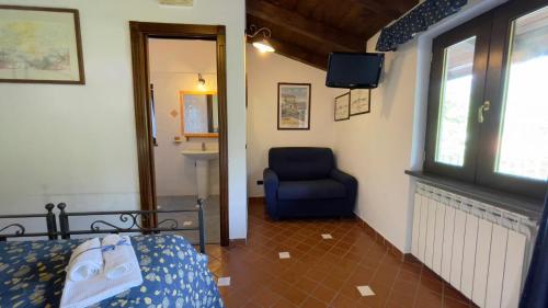 a bedroom with a blue chair and a television at Agriturismo La Casa Del Ghiro in Pimonte