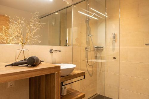 uma casa de banho com uma cabina de duche em vidro com um lavatório e um WC. em Tevini Boutique Suites by we rent em Zell am See