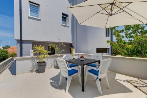 a table and chairs with an umbrella on a patio at Apartments Hemetek in Veli Lošinj