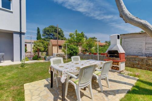 a patio with a table and chairs and a grill at Apartments Hemetek in Veli Lošinj