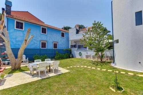 a yard with a table and chairs and a blue building at Apartments Hemetek in Veli Lošinj