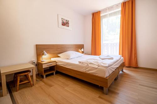 a bedroom with a bed and a window with orange curtains at Fatrapark 2 Apartments HRABOVO - Hlavná recepcia in Ružomberok