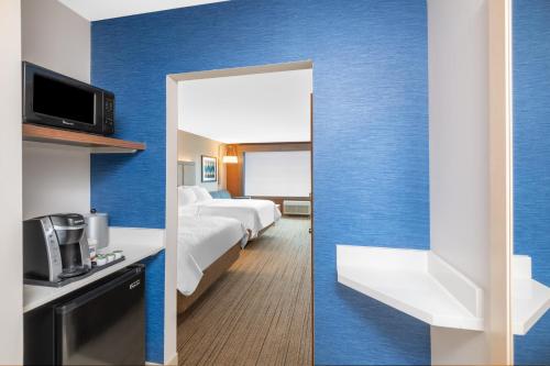 a hotel room with blue walls and a bed and a mirror at Holiday Inn Express & Suites - Phoenix - Airport North by IHG in Phoenix