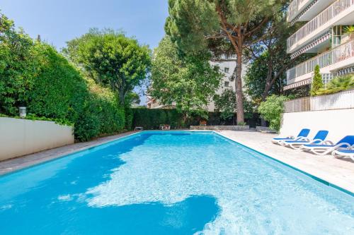une piscine avec des chaises et un bâtiment dans l'établissement Nelson Cannes YourHostHelper, à Cannes