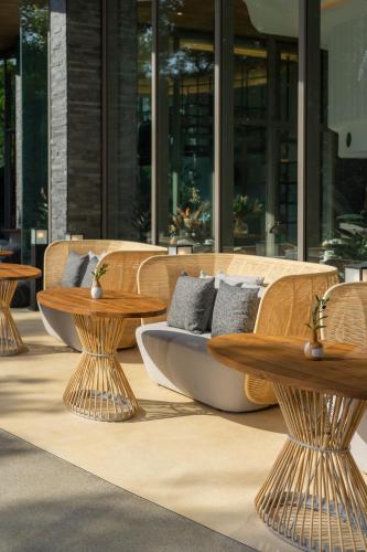 a wooden bench with benches and tables in front of a building at Bayphere Hotel Pattaya JC in Na Jomtien