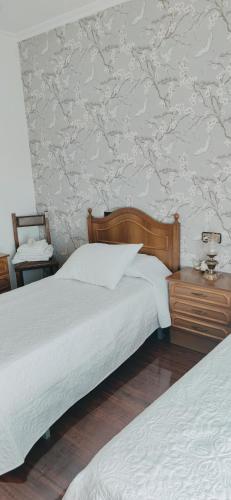 a bedroom with two beds and a wall with wallpaper at Pensión Nigrán in Nigrán