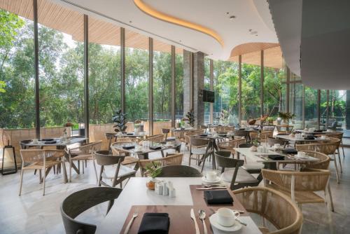a restaurant with tables and chairs and large windows at Bayphere Hotel Pattaya JC in Na Jomtien