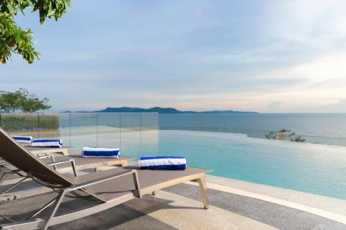 a group of lounge chairs and a swimming pool at Bayphere Hotel Pattaya JC in Na Jomtien