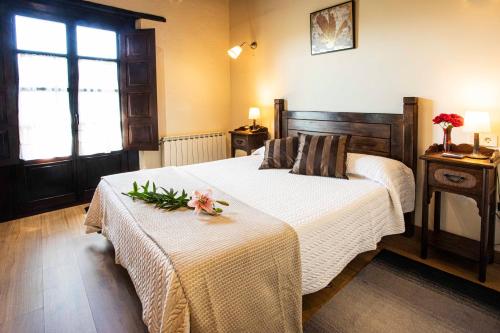 a bedroom with a bed and a table with flowers on it at La Casona de Tresgrandas in Tresgrandas