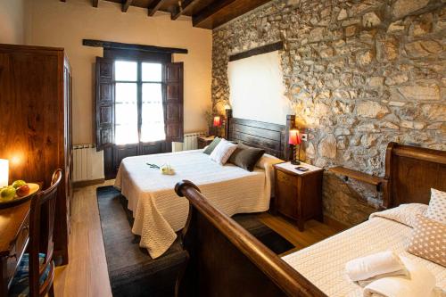 a bedroom with two beds and a stone wall at La Casona de Tresgrandas in Tresgrandas