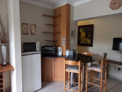 a kitchen with a table and a microwave and a refrigerator at Troas Boutique hotel in Vanderbijlpark