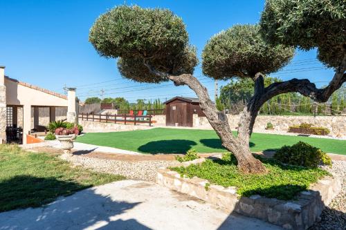 a tree in a garden with a yard at Hauzify I Mas Blau in L'Ametlla de Mar