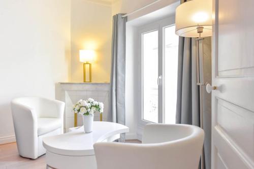 Cette chambre blanche dispose de chaises blanches, d'une table et d'une fenêtre. dans l'établissement 2-Br City center near Croisette & Palais, à Cannes