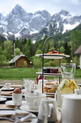 a table with plates of food on a table with mountains at Triangel Boutique Hotel in Kranjska Gora