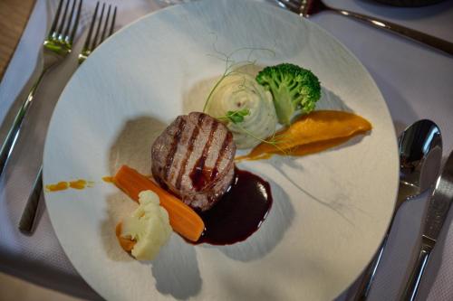 a plate of food with meat and vegetables on a table at Triangel Boutique Hotel in Kranjska Gora