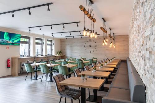a restaurant with wooden tables and green chairs at Dominik Hotel & Eventsaal in Paderborn