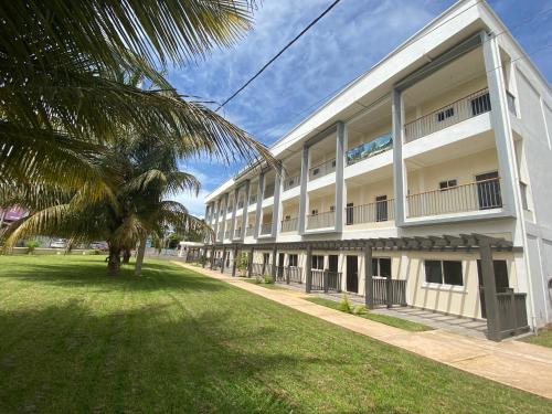 a large white building with a palm tree in front of it at Kololi Beach Resort in Kololi