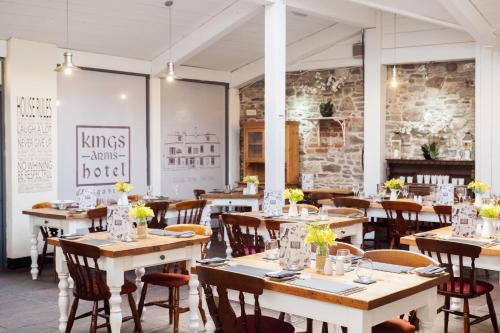 um restaurante com mesas e cadeiras de madeira e uma parede de tijolos em Kings Arms Hotel em Abergavenny