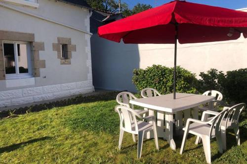 a table and chairs with a red umbrella on a yard at Charmante maison rénovée Proche plage,port,clos in Lézardrieux