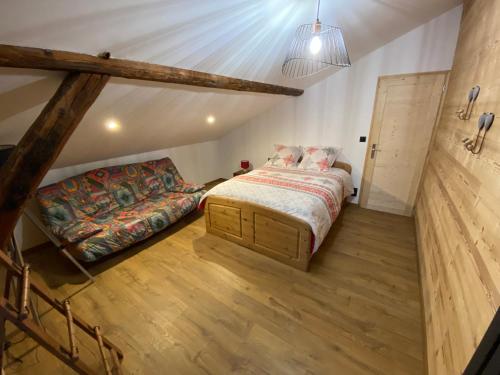 - une chambre mansardée avec un lit et un canapé dans l'établissement Appartement 75m2 duplex au cœur du village de Queige, à Queige