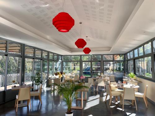 un restaurante con mesas, sillas y ventanas en L'Ortensia, en Saint-Gervais-sur-Mare