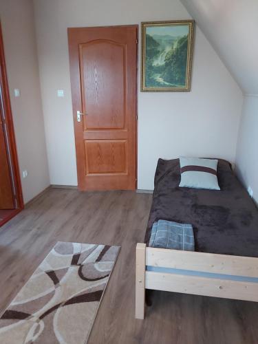 sypialnia z łóżkiem i drewnianymi drzwiami w obiekcie Számadó Vendégház w mieście Poroszló