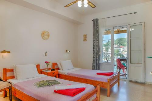 a bedroom with two beds and a balcony at MANESSIS Apartments Kassiopi Bay Corfu in Kassiopi