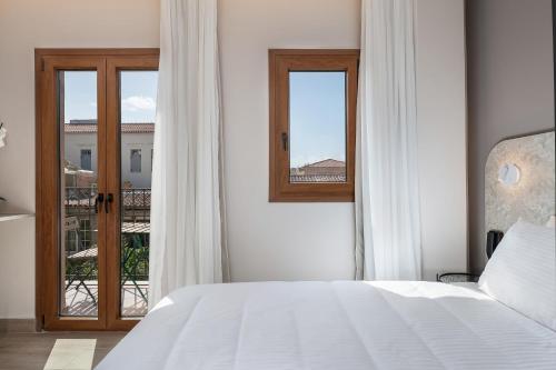 a white bedroom with a bed and a balcony at Al Daliani Minaret Rooms in Chania