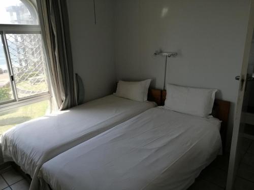 a bedroom with two white beds and a window at Seagull 312 in Margate