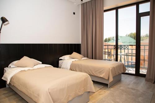 2 bedden in een hotelkamer met een balkon bij Maison in Bosteri