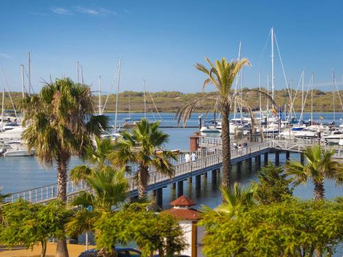 a marina with palm trees and boats in the water at Hotel Fuerte El Rompido in El Rompido