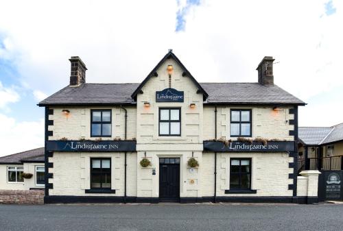 a white building with a sign on the front of it at The Lindisfarne Inn - The Inn Collection Group in Beal