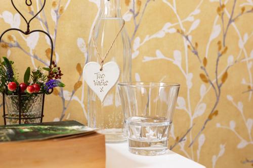 a bottle of water and a glass with a heart on it at Elder Grove in Ambleside