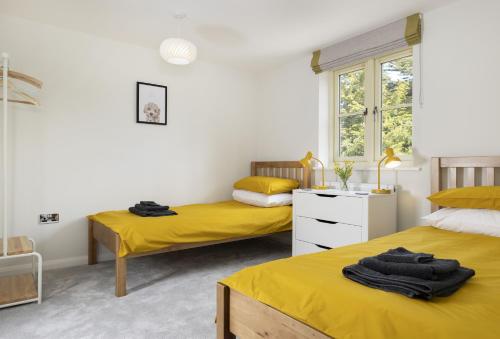 2 Betten in einem Zimmer mit gelber Bettwäsche in der Unterkunft Agatha Bear Cottage in Stow on the Wold