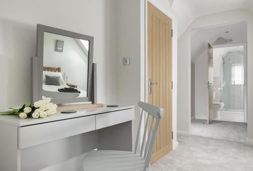 a white bathroom with a mirror and a white chair at Agatha Bear Cottage in Stow on the Wold