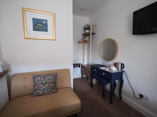 a room with a couch and a table with a mirror at Cowrie Guest House in Berwick-Upon-Tweed