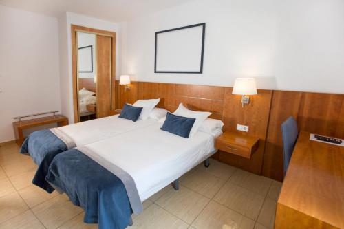 een slaapkamer met een groot wit bed met blauwe kussens bij Savoy in Alcoy