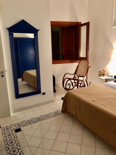 1 dormitorio con cama, espejo y silla en Sulle ali del Mediterraneo, en Marettimo