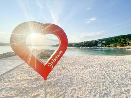 a heart shaped sign on a beach with the sun at Apartman Anđelko in Jadranovo