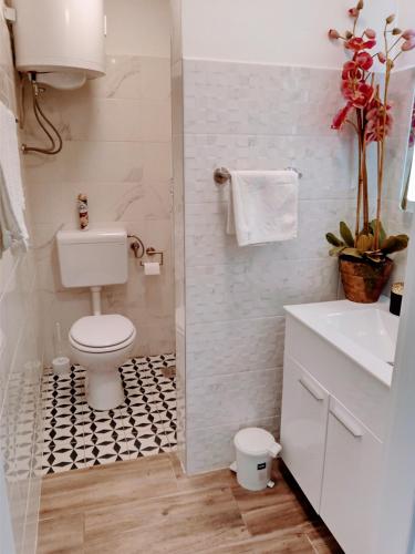 a bathroom with a toilet and a black and white tile floor at ILOVIK FLOWER in Ilovik