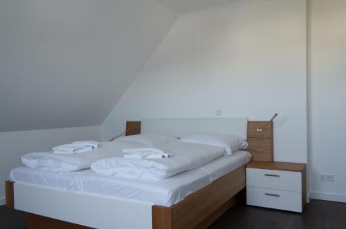 a large bed with white sheets and a night stand at Villa Insel in Börgerende-Rethwisch