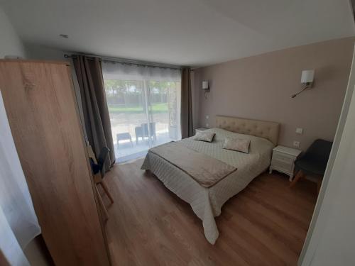 a bedroom with a bed and a large window at LA COTTINIERE in Drefféac
